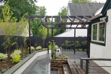 This is an example of a small contemporary back patio in Philadelphia with stamped concrete and a pergola.