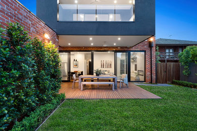 Medium sized modern back patio in Melbourne with brick paving and a roof extension.