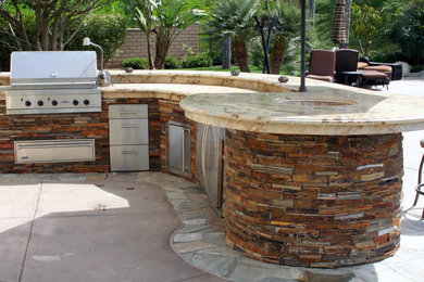 Diseño de patio mediterráneo grande sin cubierta en patio trasero con cocina exterior y adoquines de piedra natural