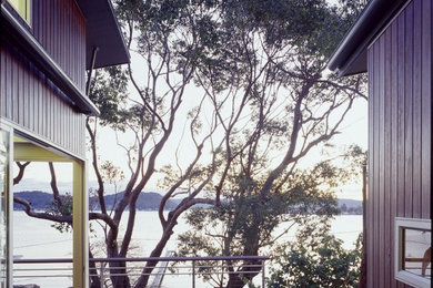 Cette image montre une terrasse en bois design de taille moyenne avec une cour et un auvent.