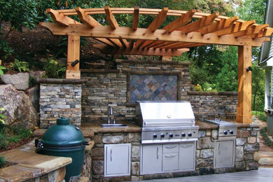 Modelo de patio clásico de tamaño medio en patio trasero con cocina exterior, entablado y pérgola