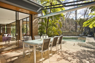 Immagine di un patio o portico design di medie dimensioni e dietro casa con fontane, pavimentazioni in pietra naturale e un parasole