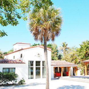 Foto di un patio o portico mediterraneo di medie dimensioni e dietro casa con un focolare, piastrelle e un tetto a sbalzo