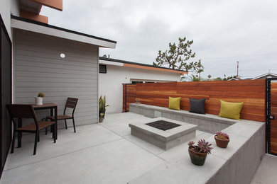 Imagen de patio contemporáneo de tamaño medio sin cubierta en patio delantero con brasero y losas de hormigón