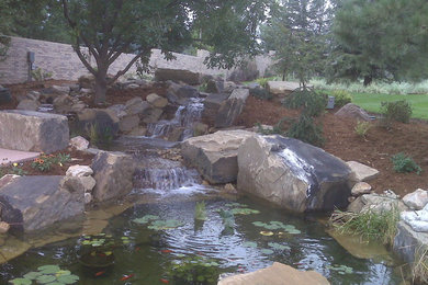 Patio fountain - large rustic backyard stone patio fountain idea in Denver with no cover