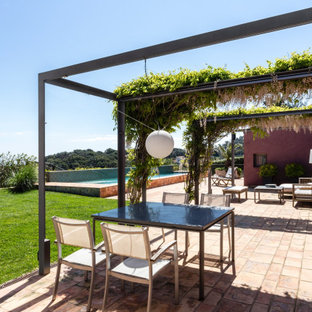 Modelo de patio contemporáneo con suelo de baldosas y pérgola