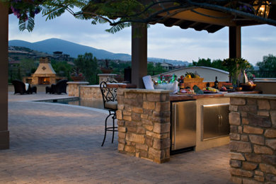 Diseño de patio tradicional renovado de tamaño medio en patio trasero con cocina exterior, adoquines de ladrillo y cenador