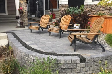 This is an example of a medium sized classic front patio in Calgary with concrete paving and no cover.