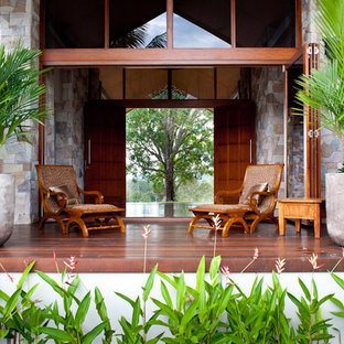 Foto di un ampio patio o portico tropicale dietro casa con fontane, pedane e un tetto a sbalzo