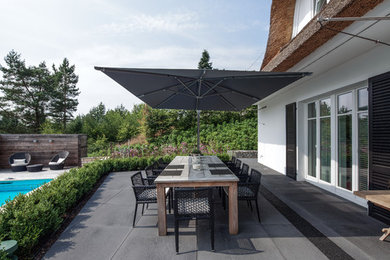 This is an example of an expansive contemporary back patio in Cologne with no cover.