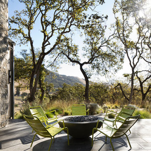 Foto di un patio o portico country in cortile con un focolare, piastrelle e nessuna copertura