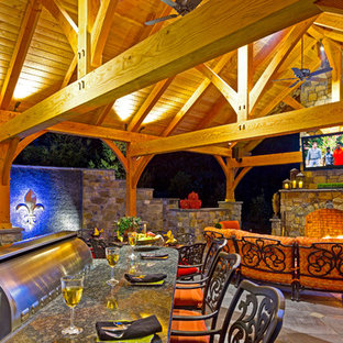Idee per un ampio patio o portico stile rurale dietro casa con un focolare e pavimentazioni in pietra naturale