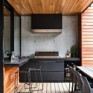 Esempio di un patio o portico contemporaneo con pedane e un tetto a sbalzo