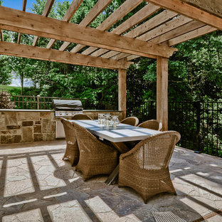 Immagine di un grande patio o portico stile americano nel cortile laterale con cemento stampato e una pergola