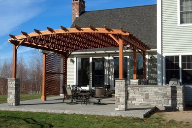 Mid-sized transitional backyard stone patio kitchen photo in Boston with a pergola