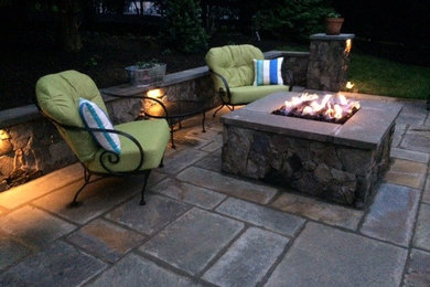 Example of a mid-sized classic backyard stone patio design in Other with a fire pit