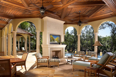 This is an example of an expansive traditional back patio in Miami with a fire feature, tiled flooring and a roof extension.