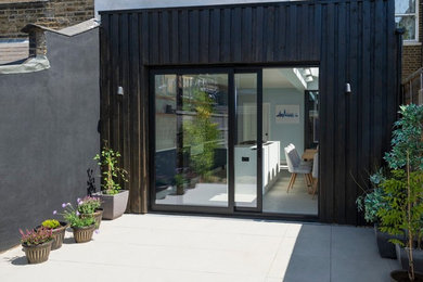 Design ideas for a medium sized contemporary back patio in Sussex with a potted garden and tiled flooring.
