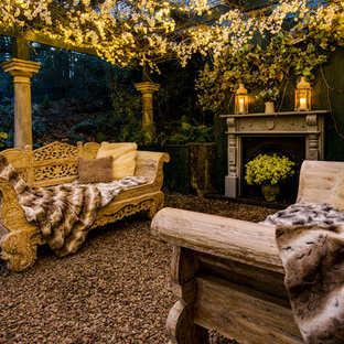 Immagine di un patio o portico stile shabby di medie dimensioni e dietro casa con ghiaia, un focolare e una pergola