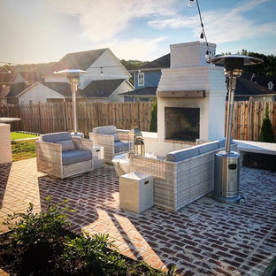Immagine di un grande patio o portico shabby-chic style dietro casa con un caminetto e pavimentazioni in mattoni