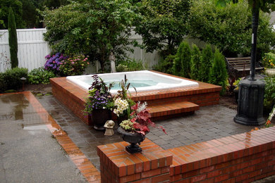 Imagen de patio clásico sin cubierta en patio trasero con fuente y adoquines de ladrillo