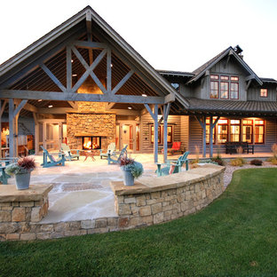 Immagine di un patio o portico country di medie dimensioni e dietro casa con un focolare, piastrelle e un tetto a sbalzo