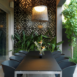 Ispirazione per un patio o portico design di medie dimensioni e dietro casa con un tetto a sbalzo e piastrelle