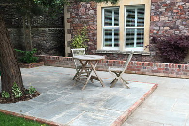 Photo of a medium sized rural back patio in Other with natural stone paving.