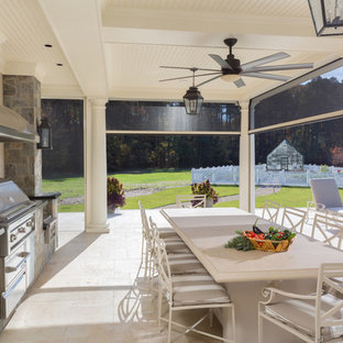 Ispirazione per un ampio patio o portico chic dietro casa con piastrelle e un tetto a sbalzo