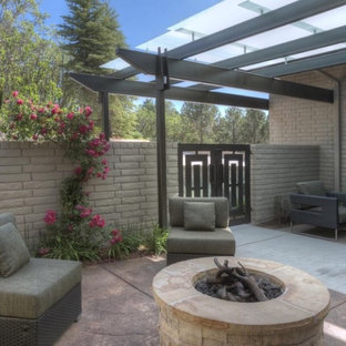 Ispirazione per un patio o portico boho chic di medie dimensioni e davanti casa con un focolare, pavimentazioni in cemento e una pergola