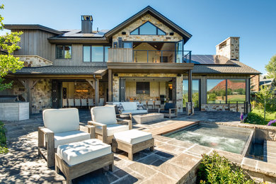 Idee per un grande patio o portico american style dietro casa con un focolare, pavimentazioni in pietra naturale e un tetto a sbalzo