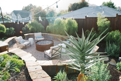 Imagen de patio de estilo americano de tamaño medio sin cubierta en patio trasero con brasero y gravilla