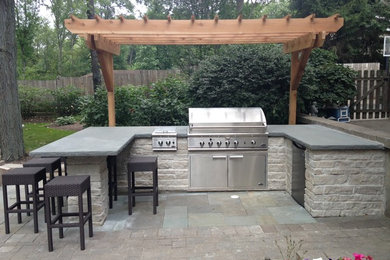 Mid-sized trendy backyard stone patio kitchen photo in Chicago with a pergola