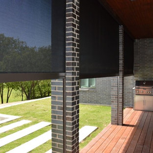 Esempio di un patio o portico chic di medie dimensioni e dietro casa con pavimentazioni in pietra naturale e un tetto a sbalzo