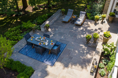 Design ideas for a large classic back patio in Chicago with a fireplace, natural stone paving and no cover.