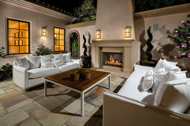 Example of a tuscan patio design in Los Angeles with no cover and a fireplace