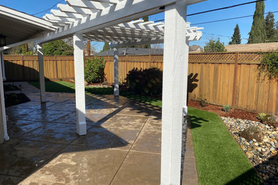 Diseño de patio de estilo americano de tamaño medio en patio trasero con suelo de hormigón estampado y pérgola