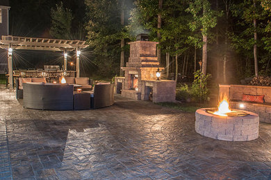 Large traditional back patio in Other with a fire feature, concrete paving and a pergola.