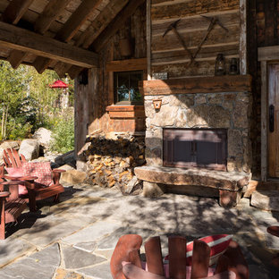 Immagine di un piccolo patio o portico rustico davanti casa con pavimentazioni in pietra naturale e un tetto a sbalzo