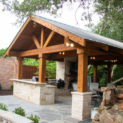 Example of a large classic backyard stone patio kitchen design in Dallas with no cover