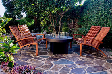 Example of a large danish backyard stone patio design in Santa Barbara with a fire pit and no cover