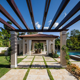 Foto di un grande patio o portico mediterraneo dietro casa con una pergola e pavimentazioni in pietra naturale