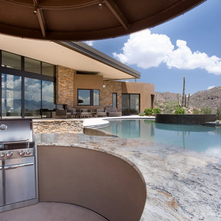 Foto di un grande patio o portico contemporaneo dietro casa con pavimentazioni in pietra naturale e un parasole