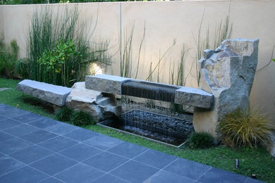 Large world-inspired courtyard patio in Los Angeles with a water feature.