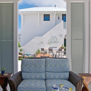 Immagine di un grande patio o portico tropicale dietro casa con un focolare, piastrelle e un tetto a sbalzo