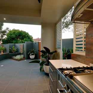 Idee per un grande patio o portico contemporaneo dietro casa con piastrelle