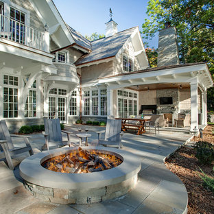 Immagine di un patio o portico classico dietro casa con pavimentazioni in pietra naturale e un tetto a sbalzo