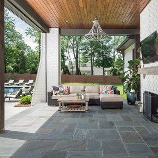 Immagine di un patio o portico country di medie dimensioni e dietro casa con un tetto a sbalzo e piastrelle