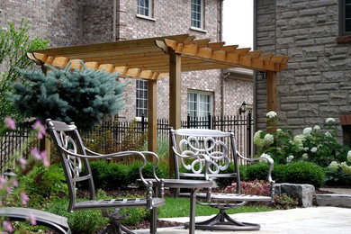 Large elegant backyard stone patio photo in Toronto with a pergola