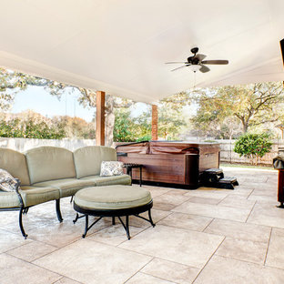 Immagine di un grande patio o portico design dietro casa con cemento stampato e un tetto a sbalzo
